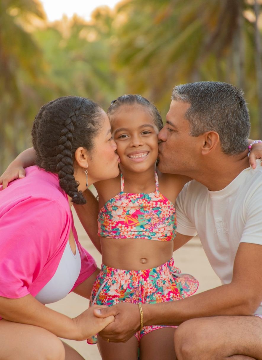 Família sorrindo na praia ao pôr do sol